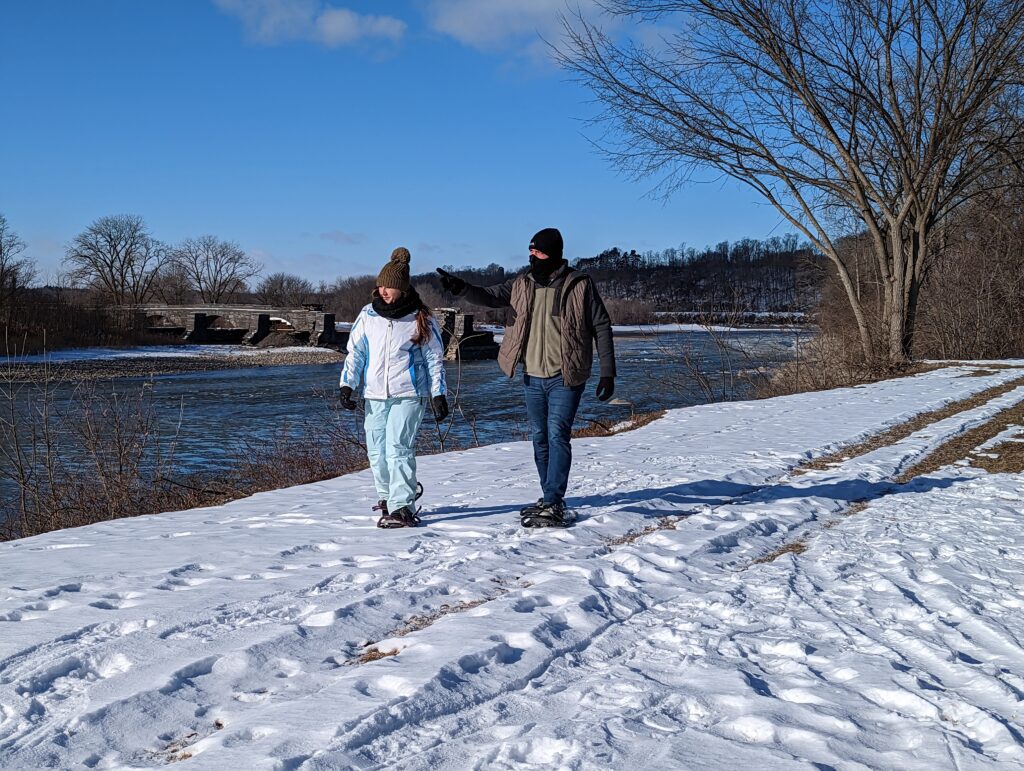 A man and a woman snowshoe at Schoharie Crossings State Historic Site. 